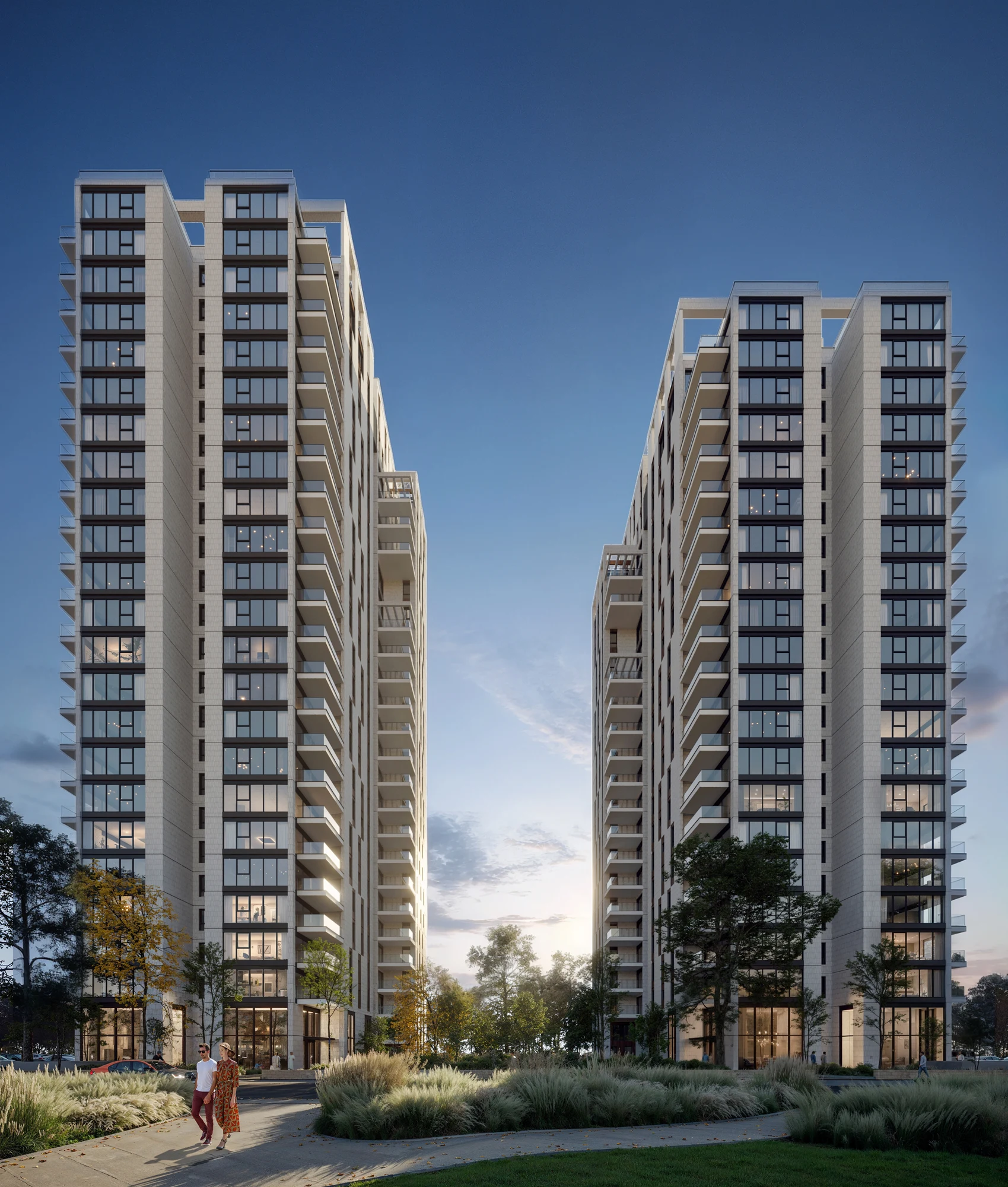 Evening view of two residential towers with warm interior lighting and landscaped grounds